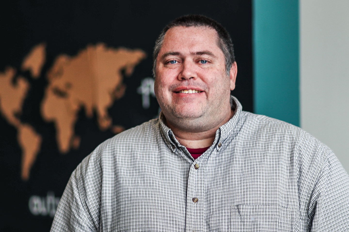 Grant Haynes in his office, a cork world map on the wall behind him