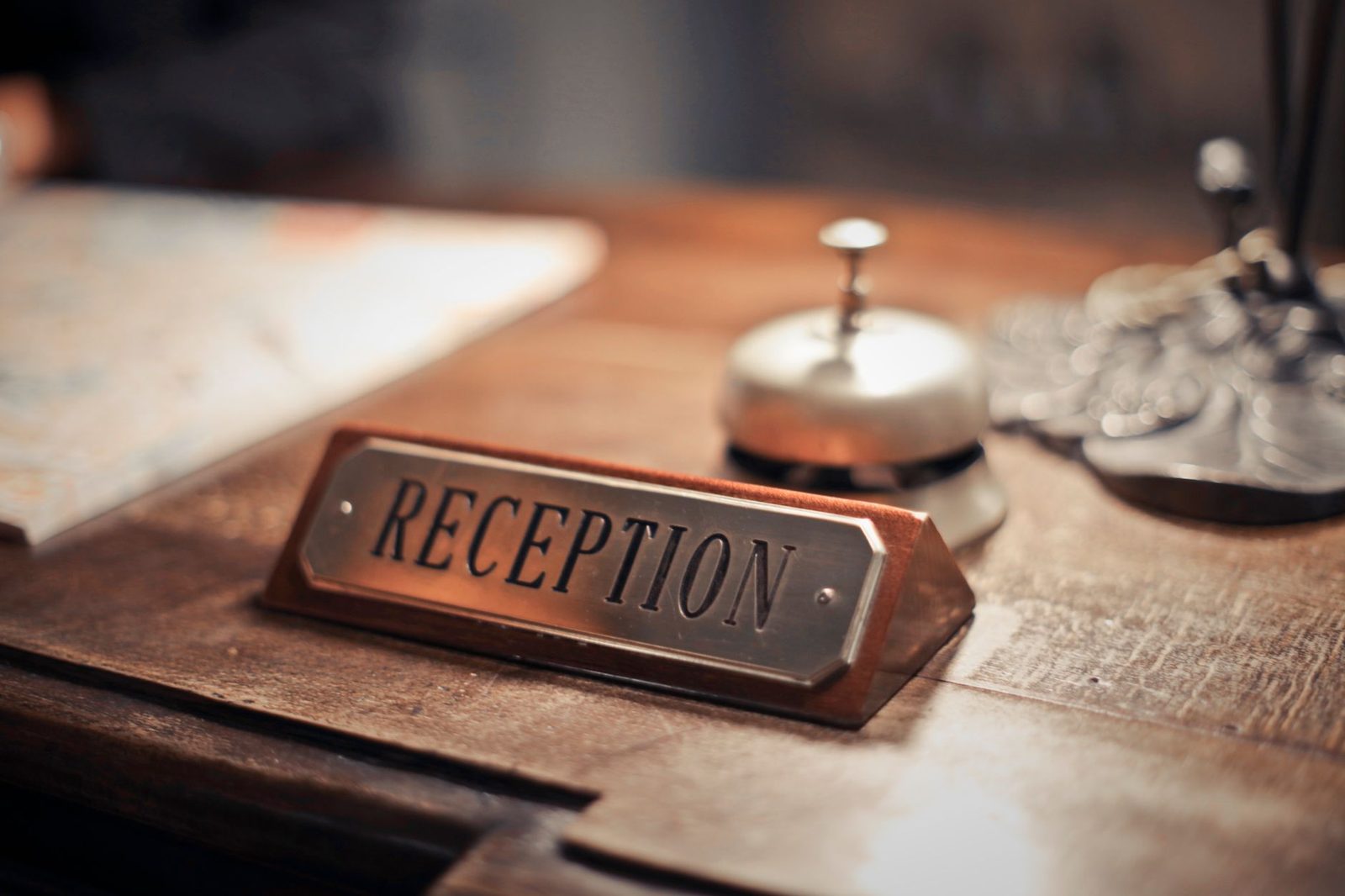 A hotel reception desk with a brass nameplate and service bell